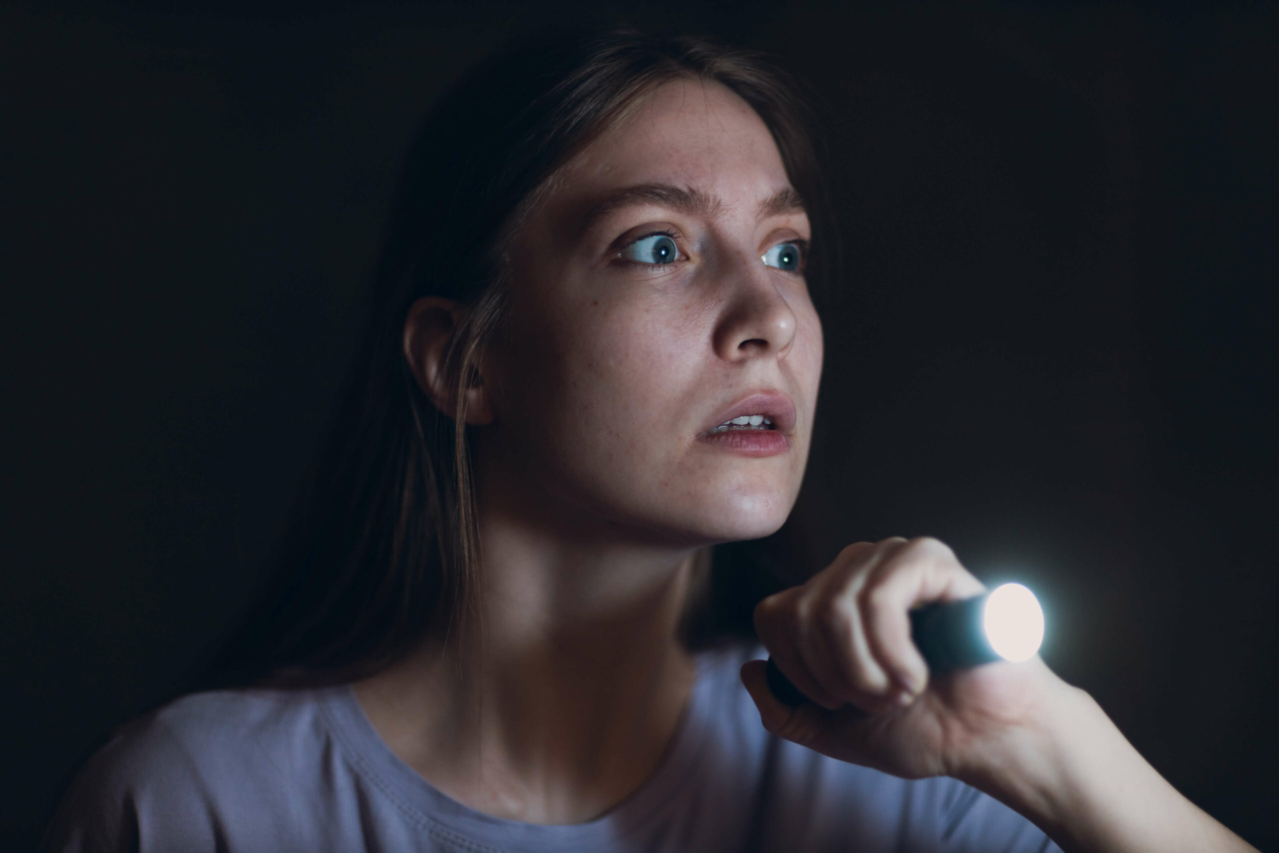Scared woman holding flashlight who needs a rape alarm
